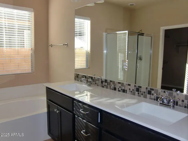 a bathroom with a sink double vanity granite tub shower and a mirror