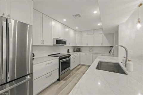 a kitchen with stainless steel appliances granite countertop a refrigerator sink and white cabinets
