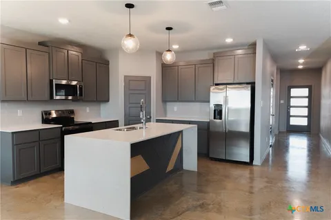 a kitchen with stainless steel appliances granite countertop a refrigerator a stove a sink and a microwave