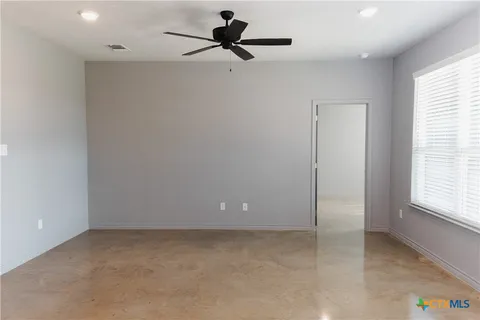 a view of a room with a ceiling fan and window