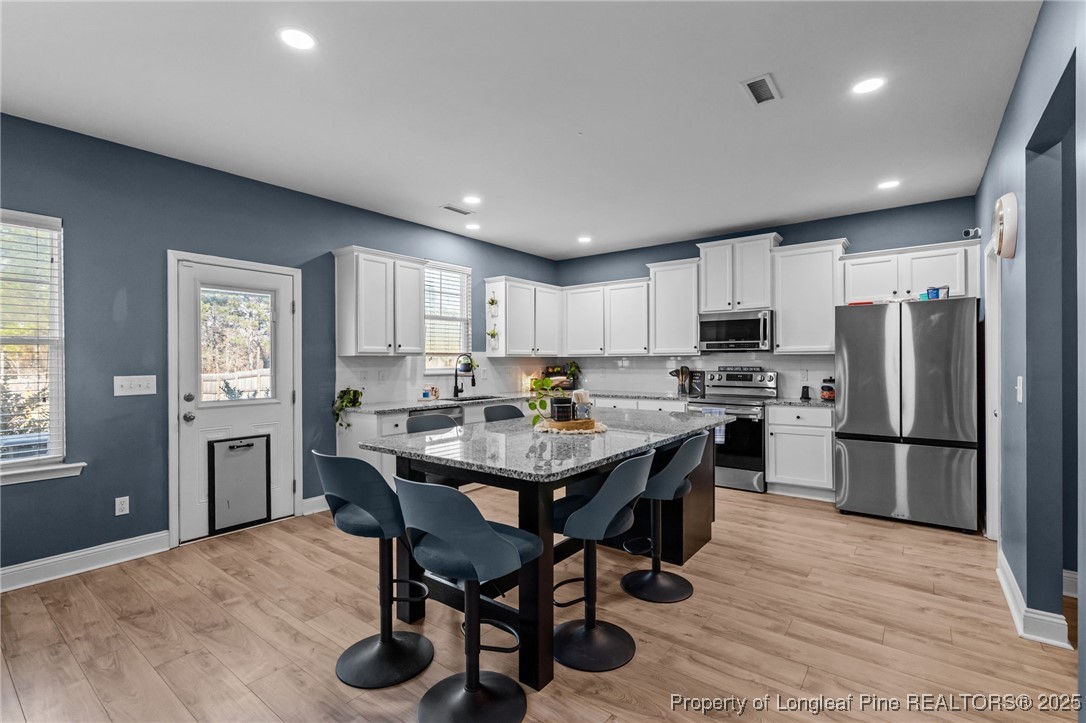 240 Heathrow Drive Spring Lake, NC 28390 - Photo 14 of 47 a kitchen with stainless steel appliances a dining table chairs refrigerator and cabinets