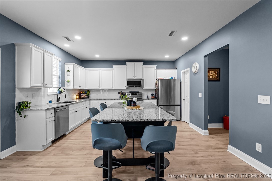 240 Heathrow Drive Spring Lake, NC 28390 - Photo 15 of 47 a large kitchen with kitchen island granite countertop furniture a refrigerator a dining table and chairs