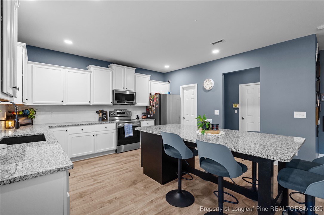240 Heathrow Drive Spring Lake, NC 28390 - Photo 16 of 47 a kitchen with granite countertop kitchen island stainless steel appliances a sink counter space and living room