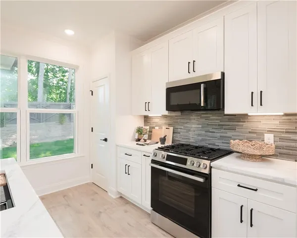a kitchen with stainless steel appliances white cabinets and a stove top oven
