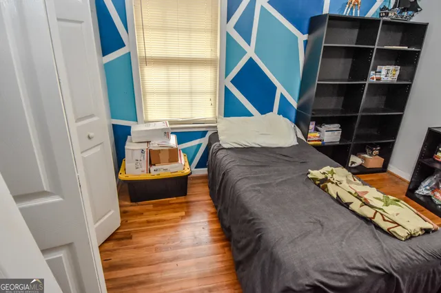 a bed sitting in a bedroom next to a window with chair
