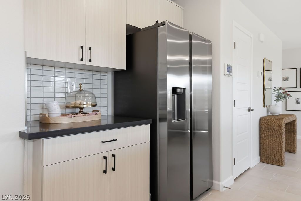 913 Cadence View Way Henderson, NV 89011 - Photo 21 of 46 A sleek, stainless steel refrigerator complements the modern kitchen cabinetry and tiled backsplash.