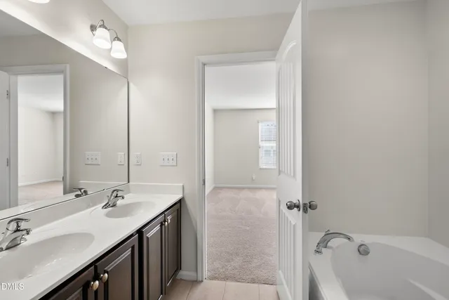 a bathroom with a tub a sink and mirror