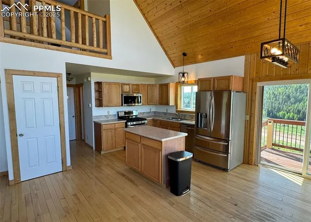 a kitchen with granite countertop a refrigerator and wooden floors