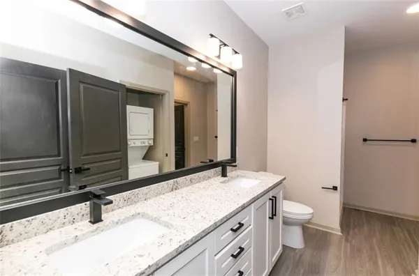 a bathroom with a granite countertop sink a large mirror and toilet