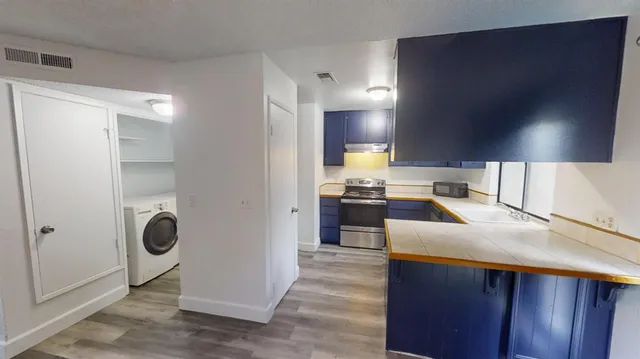 a kitchen with kitchen island granite countertop wooden cabinets a sink a stove and a refrigerator