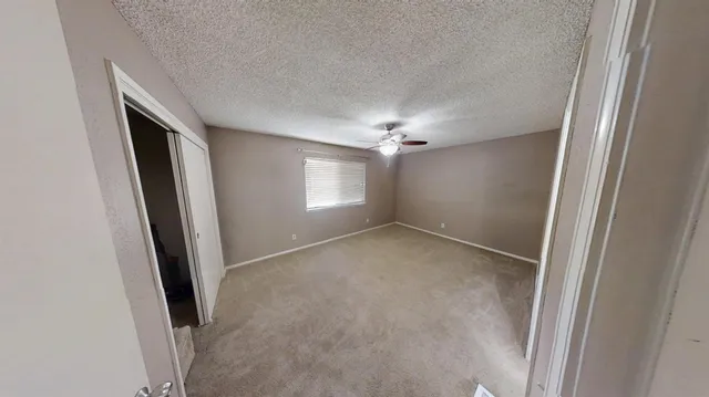 an empty room with windows and chandelier fan