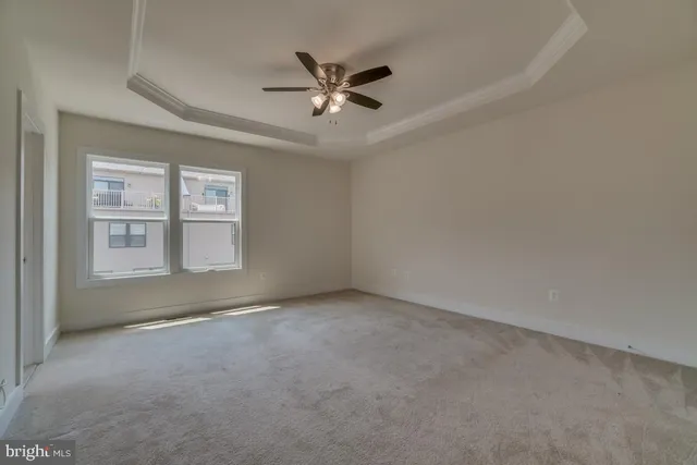 an empty room with ceiling fan and windows