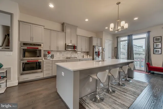 a kitchen with stainless steel appliances granite countertop a stove top oven a sink dishwasher a dining table and chairs with wooden floor