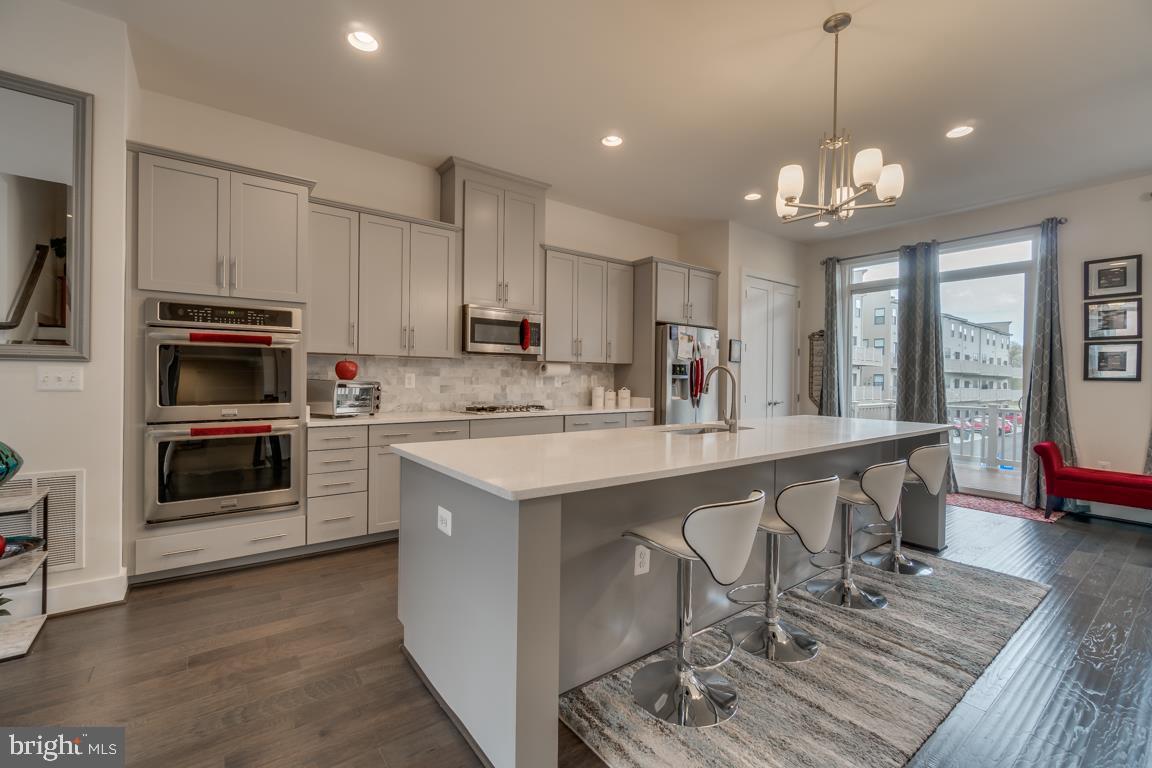 44721 Ellsworth Terrace Ashburn, VA 20147 - Photo 7 of 51 a kitchen with stainless steel appliances granite countertop a stove top oven a sink dishwasher a dining table and chairs with wooden floor