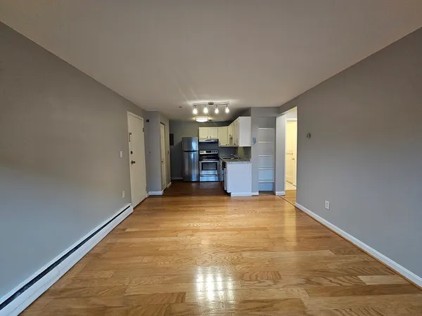 a view of empty room with kitchen and window