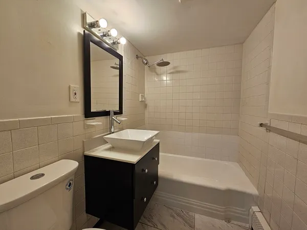 a bathroom with a granite countertop sink a toilet and shower