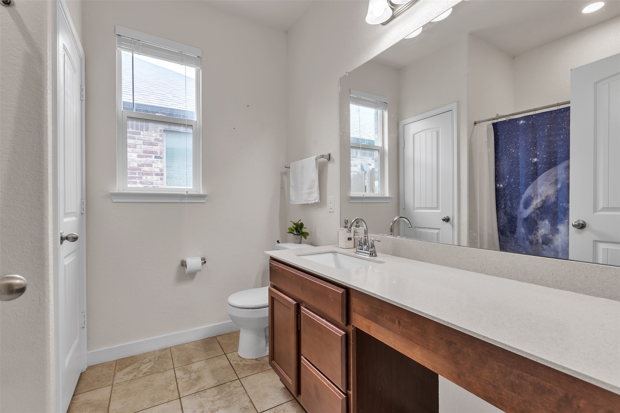 128 Kavanaugh Street Georgetown, TX 78628 - Photo 12 of 13 Bathroom featuring a wood-finish vanity with a light-toned countertop, a full-width mirror, and tile flooring