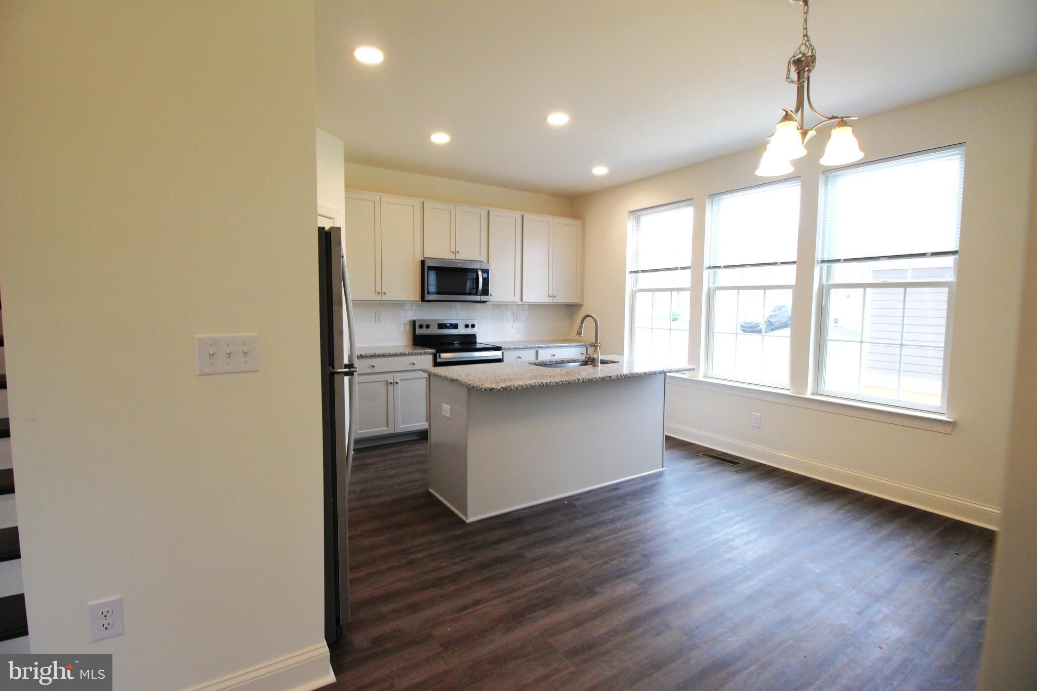 851 Mapleton Avenue Middletown, DE 19709 - Photo 9 of 26 a kitchen with stainless steel appliances granite countertop a stove a sink a refrigerator white cabinets and wooden floor