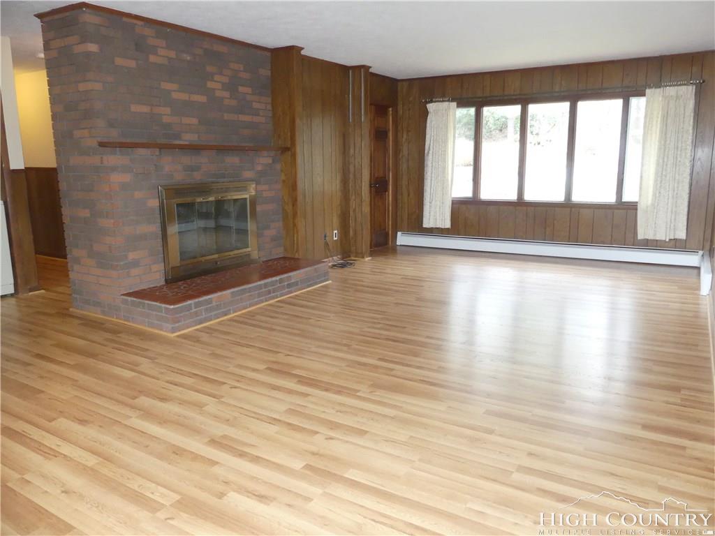 567 Deck Hill Road Boone, NC 28607 - Photo 2 of 25 a view of empty room with wooden floor and fireplace