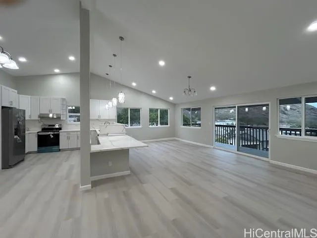 a large hall with stainless steel appliances kitchen island a large counter top a stove and a wooden floors