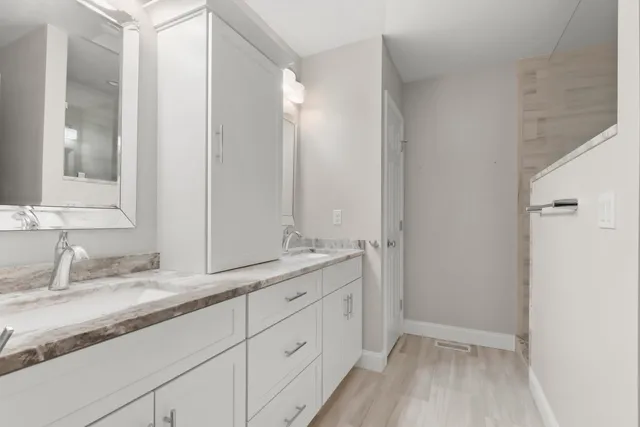 a bathroom with a granite countertop sink mirror and cabinets
