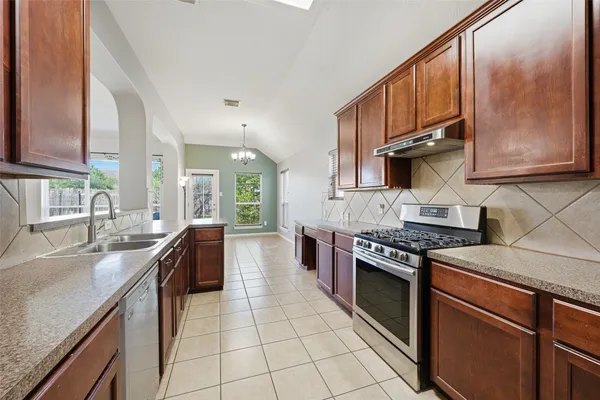 a large kitchen with granite countertop a sink and dishwasher a stove top oven with wooden floor