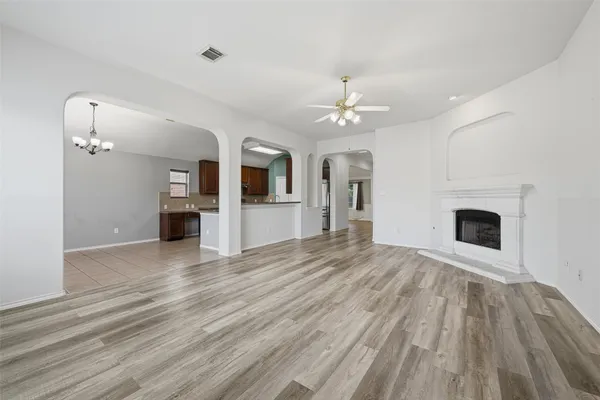 a view of an empty room with wooden floor and a fireplace