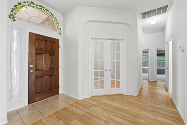 an empty room with wooden floor closet and windows