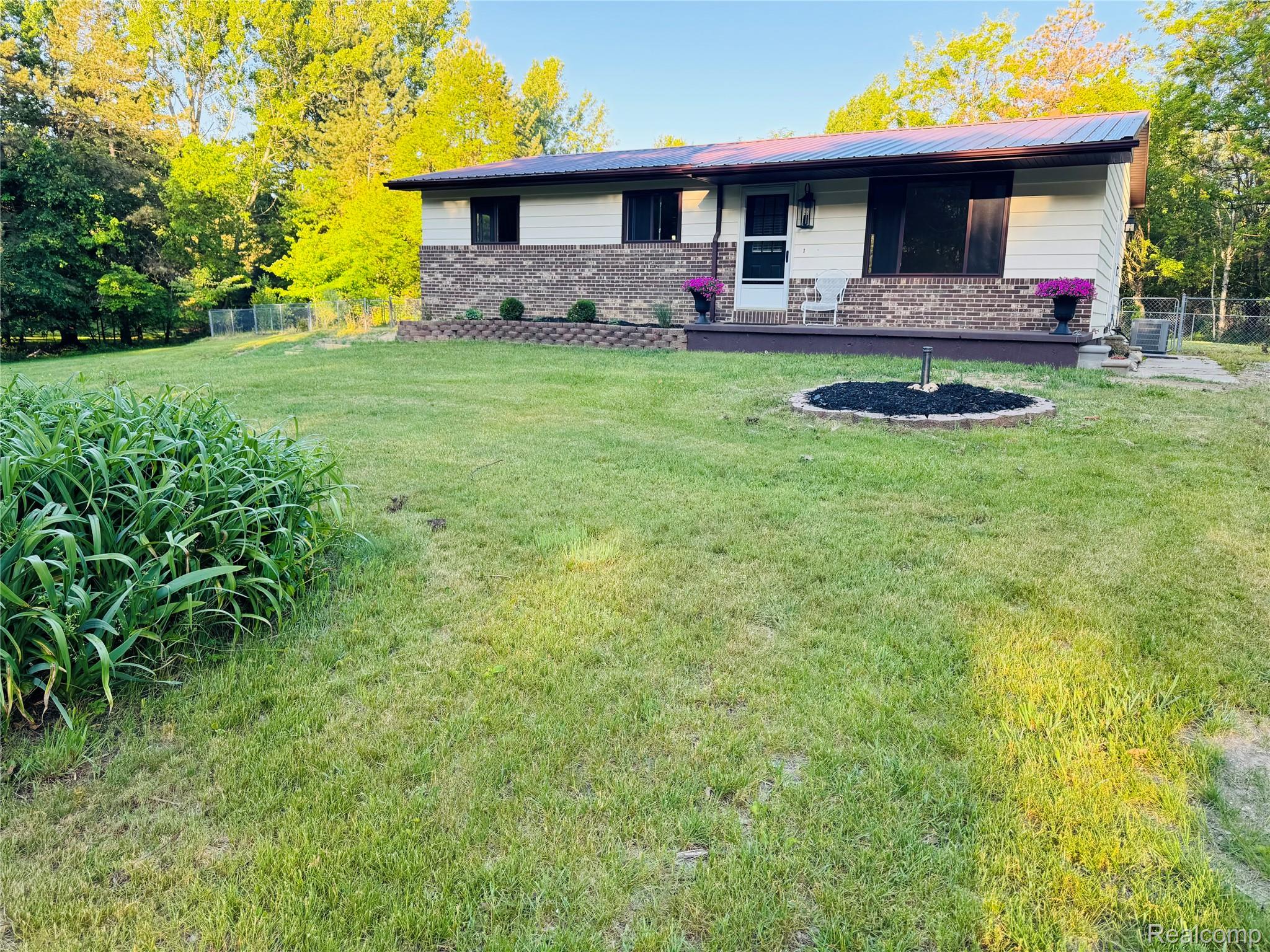 5215 Schlaud Road North Branch, MI 48461 - Photo 1 of 14 Ranch-style exterior featuring a metal roof, brick and siding facade, and a covered porch