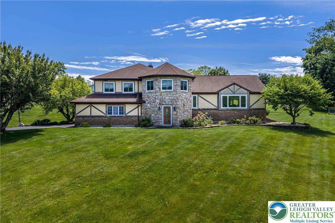 A stately manor with a grand stone turret entrance, set against a manicured green lawn.