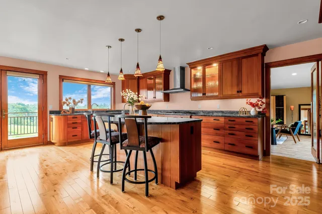 a open kitchen with stainless steel appliances granite countertop a stove top oven a sink dishwasher a dining table and chairs with wooden floor