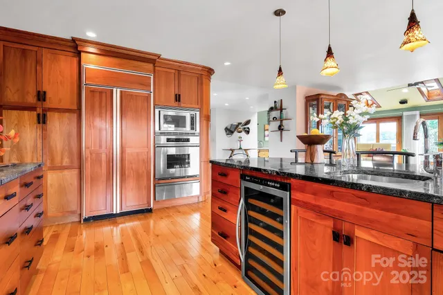 a kitchen with stainless steel appliances granite countertop a refrigerator a sink dishwasher and a wooden cabinets