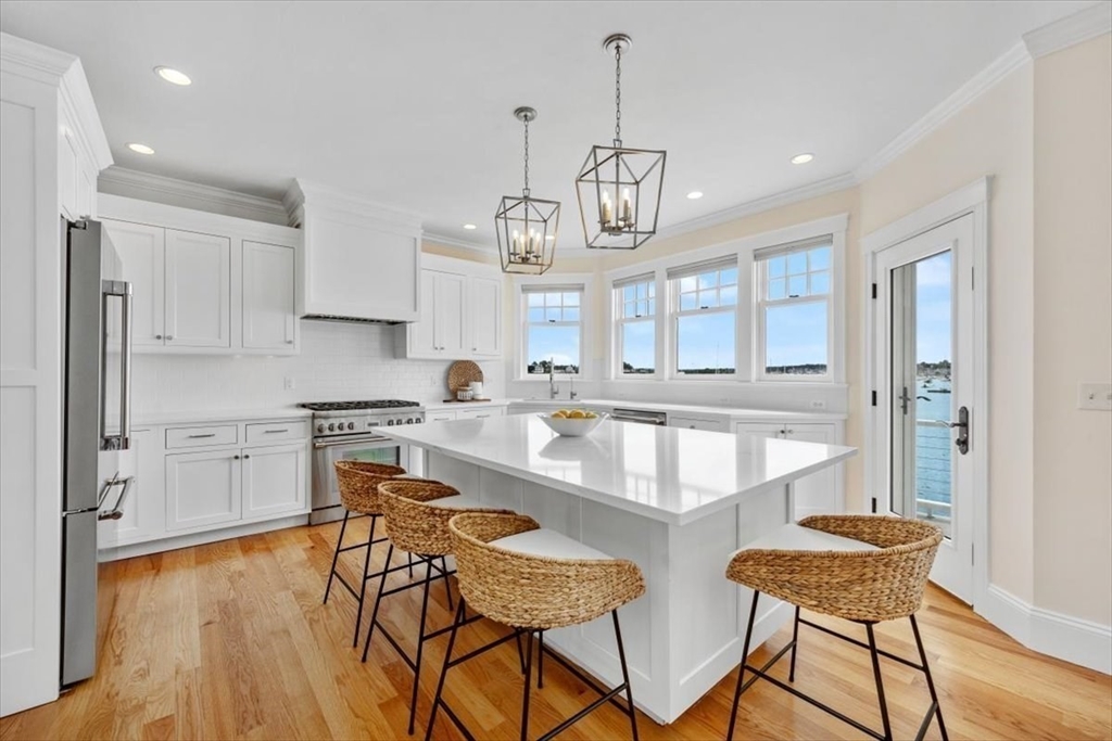 86 Lighthouse Road Scituate, MA 02066 - Photo 3 of 38 a large kitchen with stainless steel appliances kitchen island granite countertop a table chairs in it and wooden floors