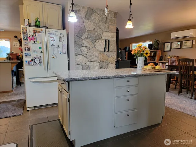 a kitchen with stainless steel appliances kitchen island granite countertop a refrigerator a sink dishwasher and white cabinets with wooden floor