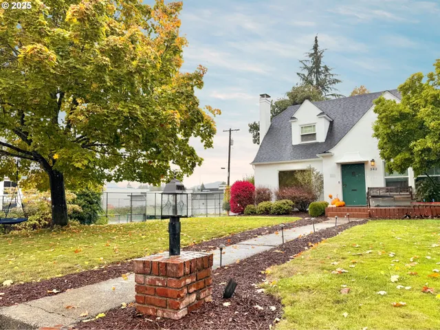 a view of a house with a big yard and large tree
