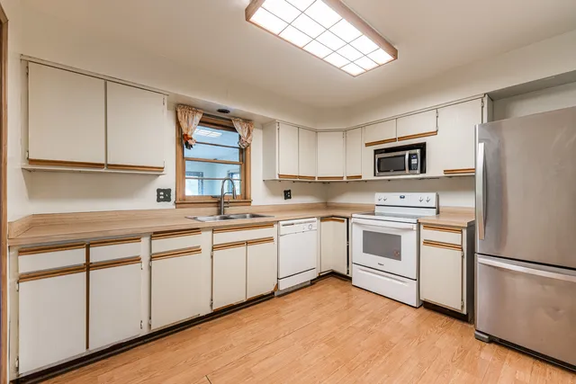 a kitchen with a sink appliances cabinets and a window