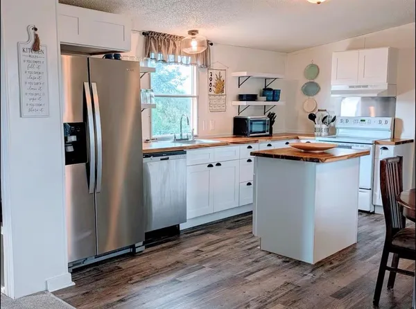 a kitchen with stainless steel appliances granite countertop a refrigerator a sink and a stove with wooden floors