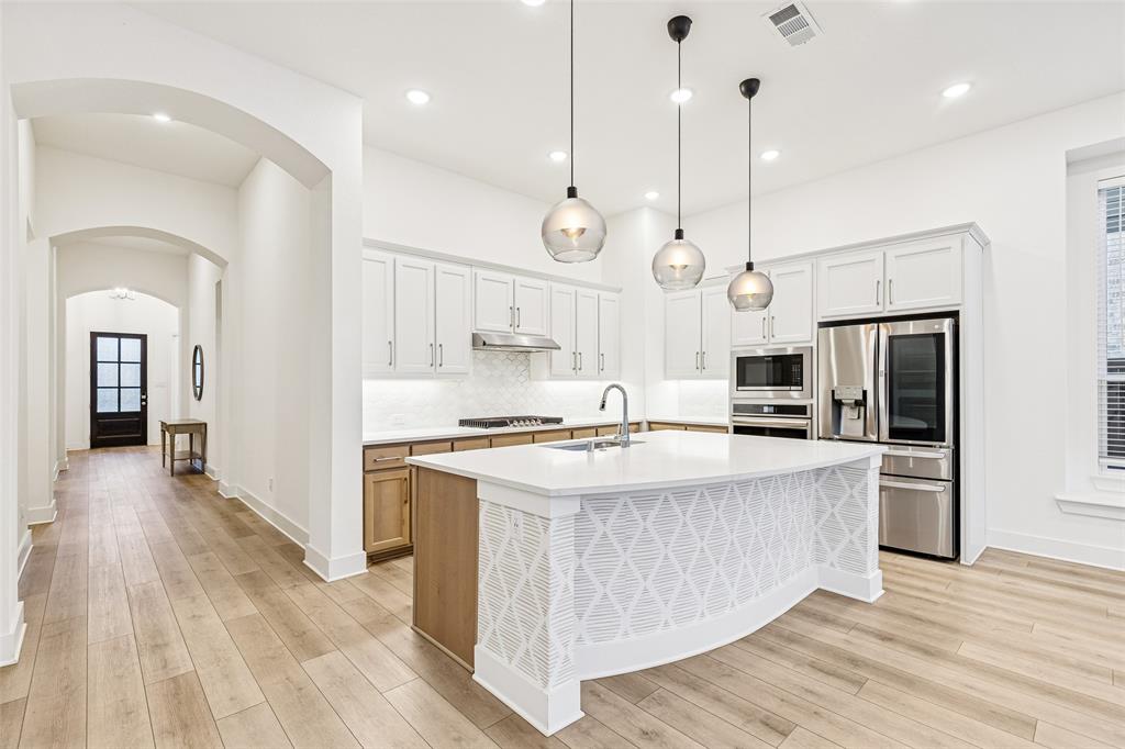 1144 Saddle Ridge Drive Aubrey, TX 76227 - Photo 3 of 34 a kitchen with stainless steel appliances kitchen island a island in the center and wooden floors