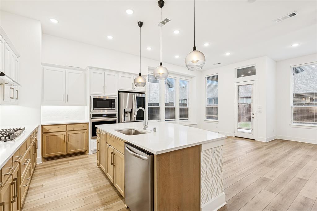 1144 Saddle Ridge Drive Aubrey, TX 76227 - Photo 4 of 34 a large kitchen with kitchen island a stove a sink a center island a stove and a center island