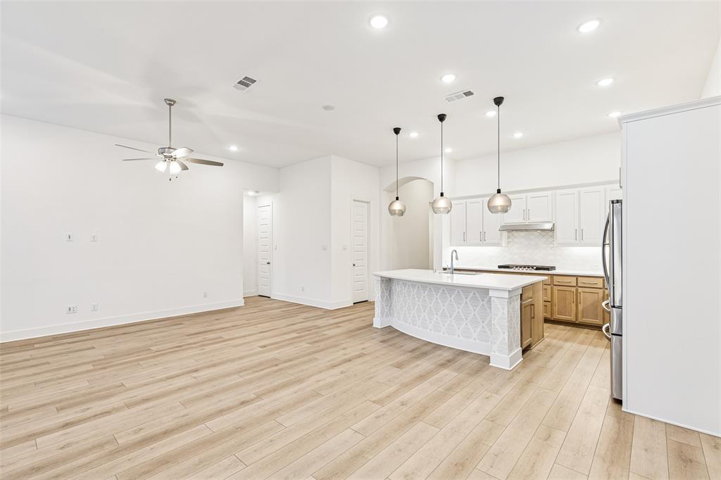 1144 Saddle Ridge Drive Aubrey, TX 76227 - Photo 7 of 34 a large kitchen with kitchen island a sink dishwasher a refrigerator and white cabinets with wooden floor