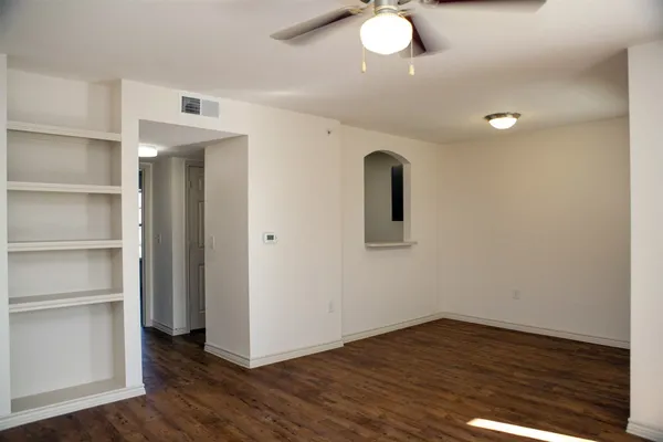 a view of an empty room with a window and wooden floor