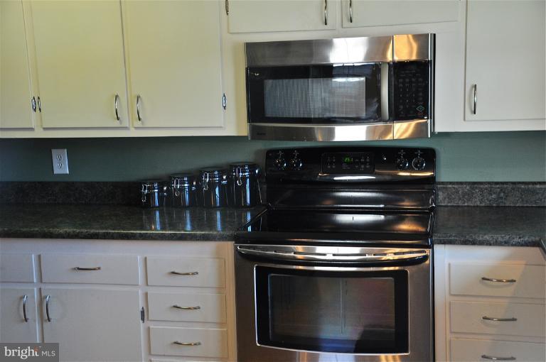 779 Masons Beach Road Deale, MD 20751 - Photo 8 of 14 a kitchen with granite countertop white cabinets stainless steel appliances and sink