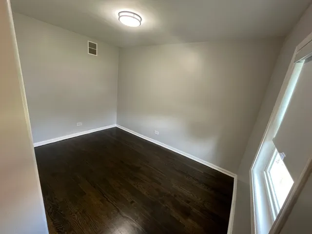 en empty room with wooden floor and windows