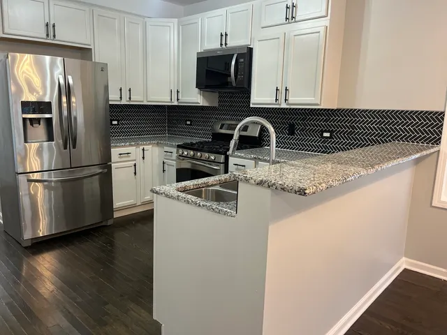 a kitchen with stainless steel appliances granite countertop a refrigerator sink and stove