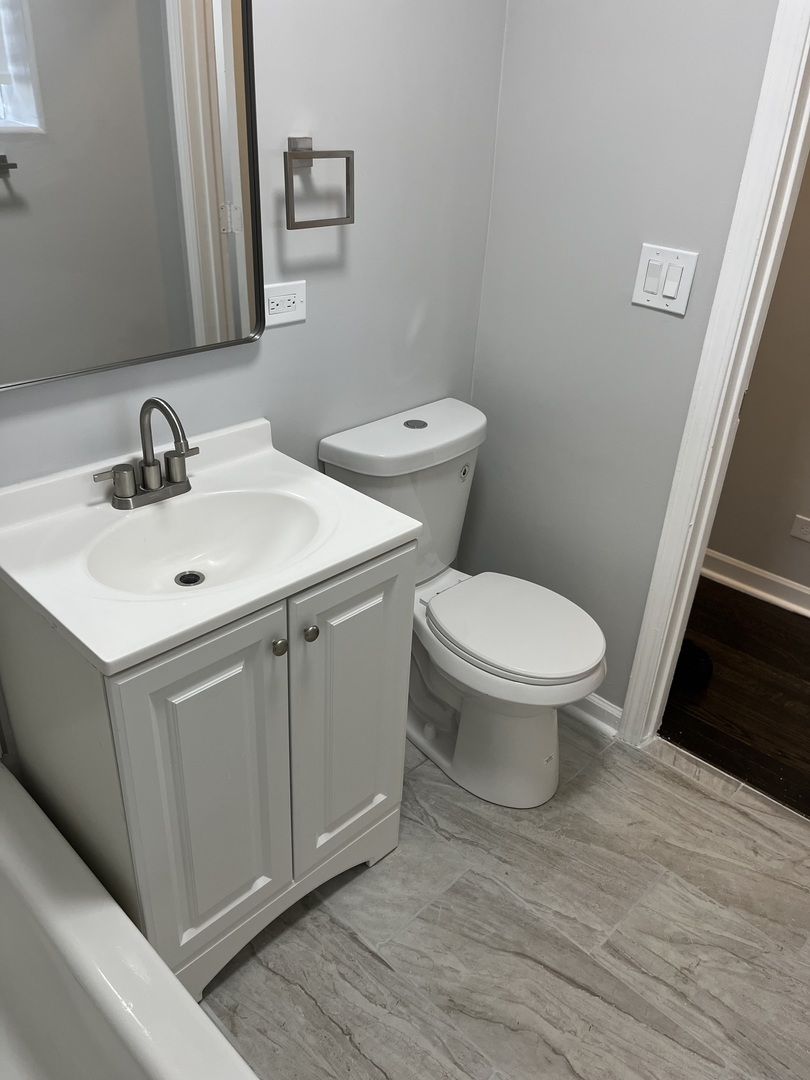 1249 South Kolin Avenue, Unit 1 Chicago, IL 60623 - Photo 9 of 20 a bathroom with a toilet sink and mirror