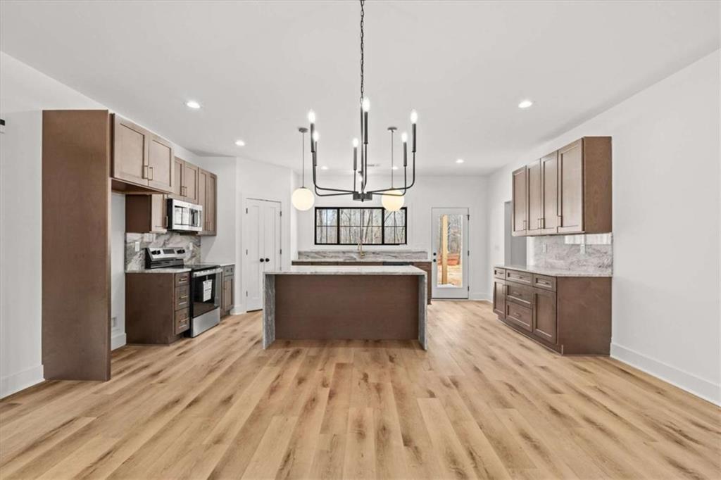415 Lively Road Waco, GA 30182 - Photo 11 of 49 a large kitchen with stainless steel appliances kitchen island a large counter tops a stove a sink cabinets and a wooden floor