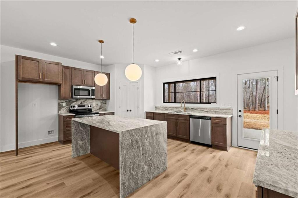 415 Lively Road Waco, GA 30182 - Photo 14 of 49 a large kitchen with stainless steel appliances kitchen island granite countertop a stove a sink dishwasher and a refrigerator with wooden floor