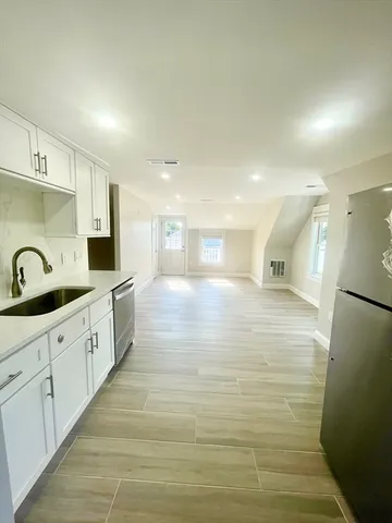 a large white kitchen with cabinets a sink and a refrigerator