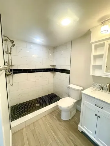 a bathroom with a sink a toilet a mirror and shower
