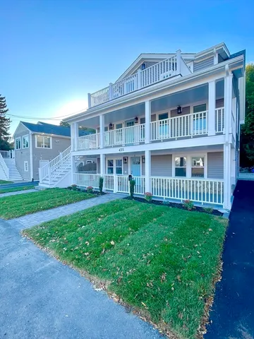 a view of an apartment with a big yard and large trees